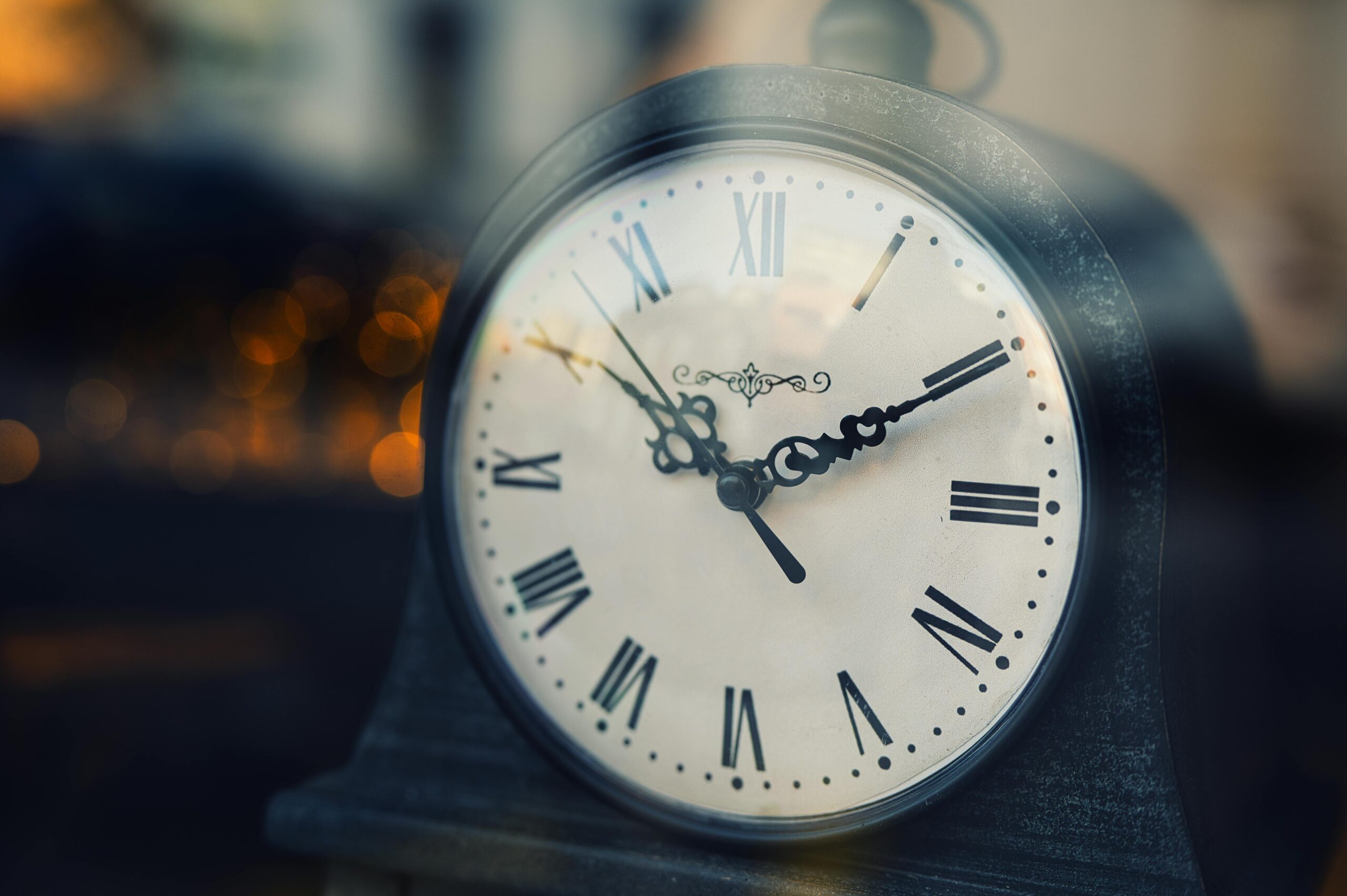 Close-up of a vintage clock with Roman numerals, softly lit background.